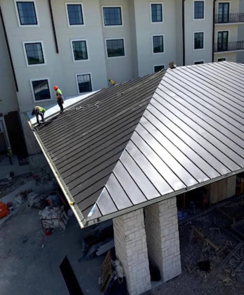 Crew installing standing seam metal roof panels on a commercial project in Hawthorn Woods